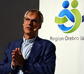John Holmberg föreläser, en bild på Region Örebro läns logotyp i bakgrunden.
