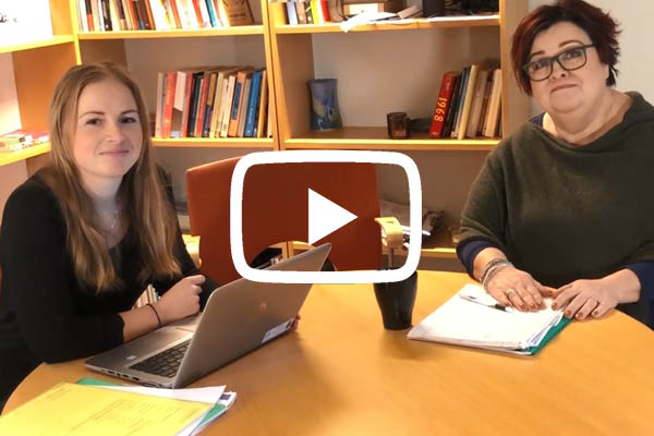 Skärmklipp från filmen där Lena Uvhagen och Lotta Karlsson-Andersson sitter vid ett bord i kontorsmiljö.